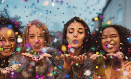 four culturally diverse women with confetti in the background
