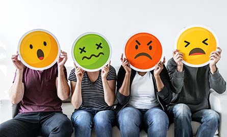 people holding up cut outs of faces with different emotions on them