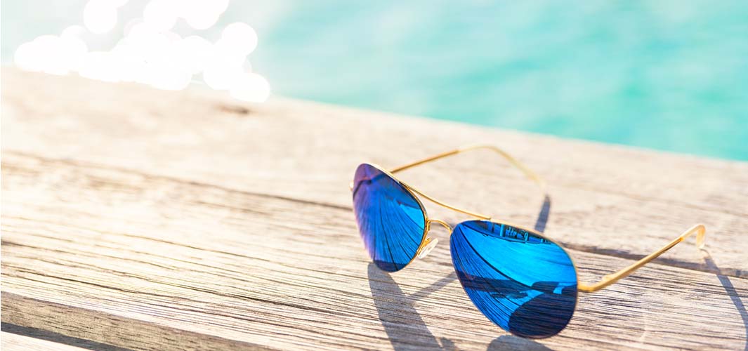 Sunglasses resting on a wooden plan on a sunny day